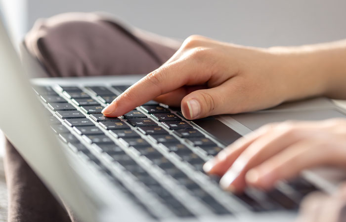 Hands typing on a laptop, representing the act of sharing or reading clever comebacks online.