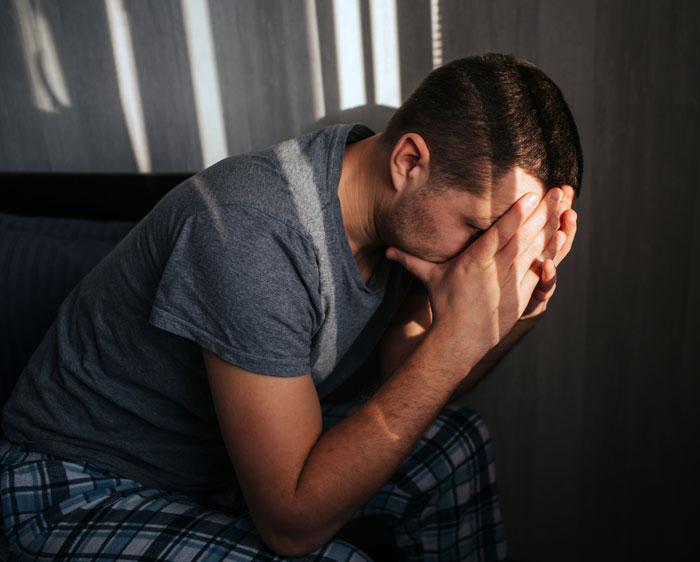 A man sitting in despair, face in his hands, reflecting the regret of men who walked out after having a baby.