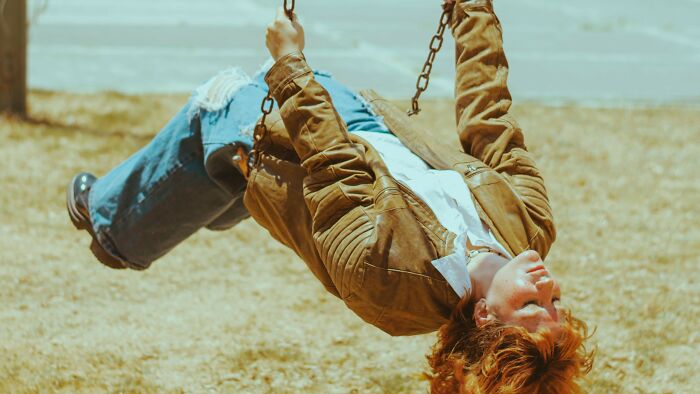 Woman swinging upside down, judging dating scenarios by their red, green, and beige flags.