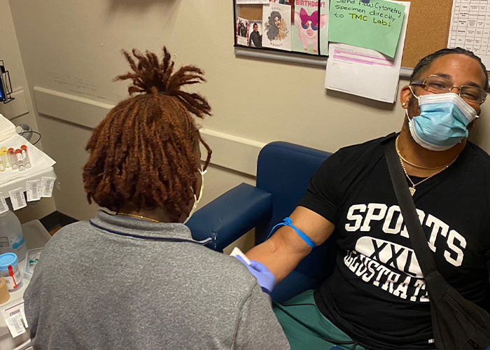 A man needing a transplant getting blood drawn by a medical professional. He is wearing a mask and a t-shirt.