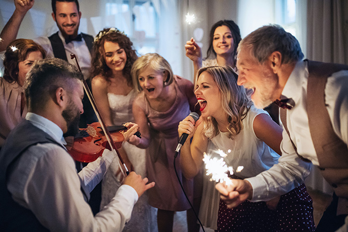 A joyous wedding celebration with a woman singing into a microphone and a man playing the violin.