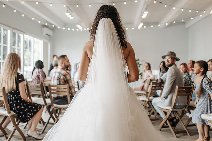 A bride faces guests at her wedding, waiting for the dance floor to open, highlighting wedding anticipation.