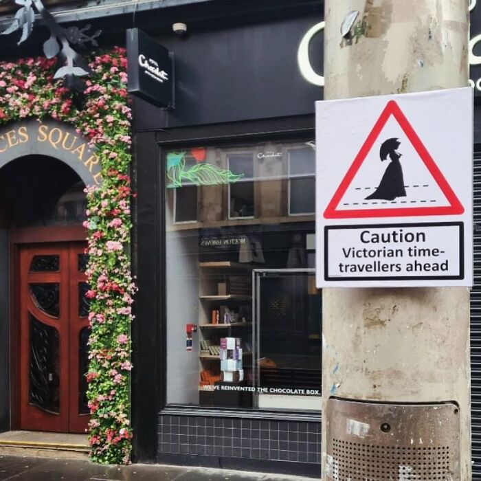 Absurd signs: A street pole with a sign warning about Victorian time-travellers outside a chocolate shop.
