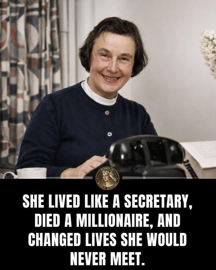 Smiling woman at a desk with a phone and flowers, symbolizing overlooked women in history.