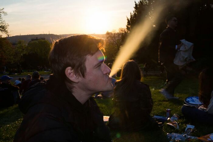 A street photographer captures a serendipitous moment of a man exhaling vapor at sunset in everyday life.