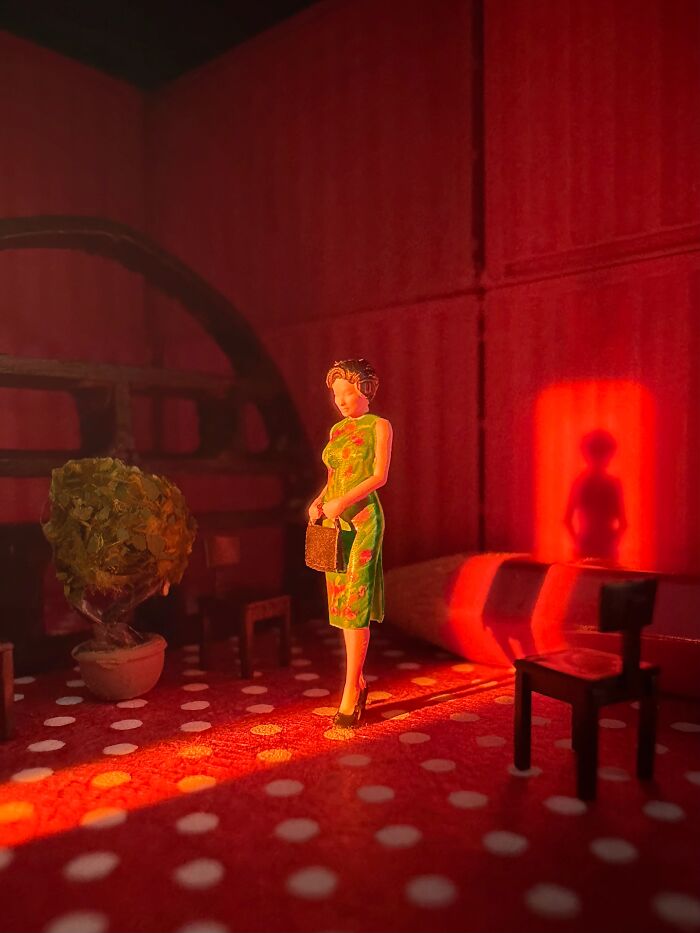 Artist Derrick Lin's office desk transforms into diorama sets, featuring a woman in a green dress in a red room.