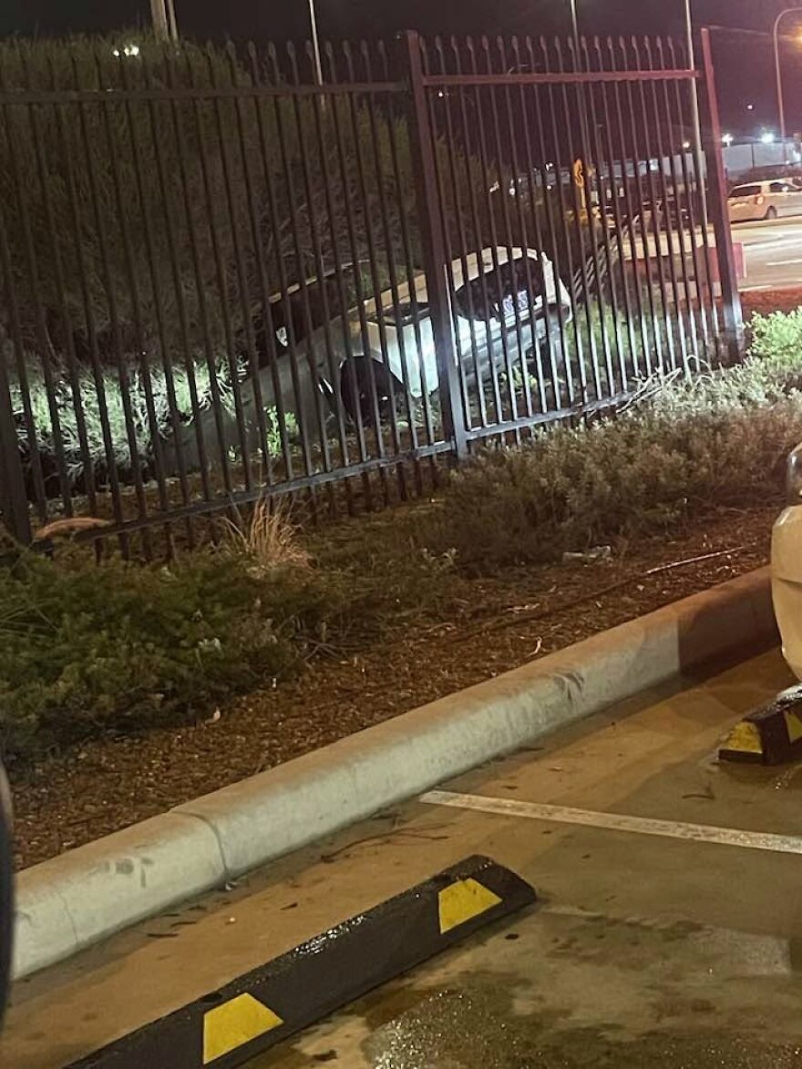 A car crashed through a metal fence at night, a rough day behind the wheel.