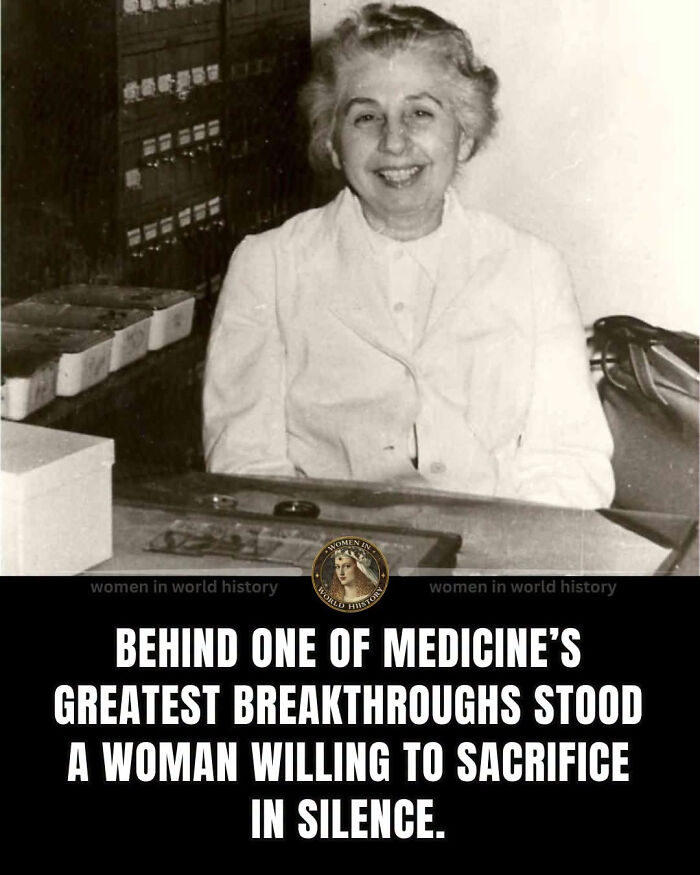 A smiling woman in history, overlooked in medical history, sitting at a desk with scientific equipment.