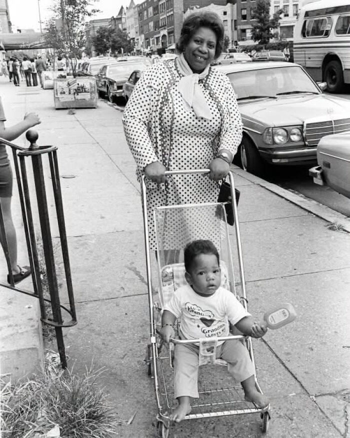 An older woman pushes a baby in a stroller, representing overlooked women in history and their everyday lives.