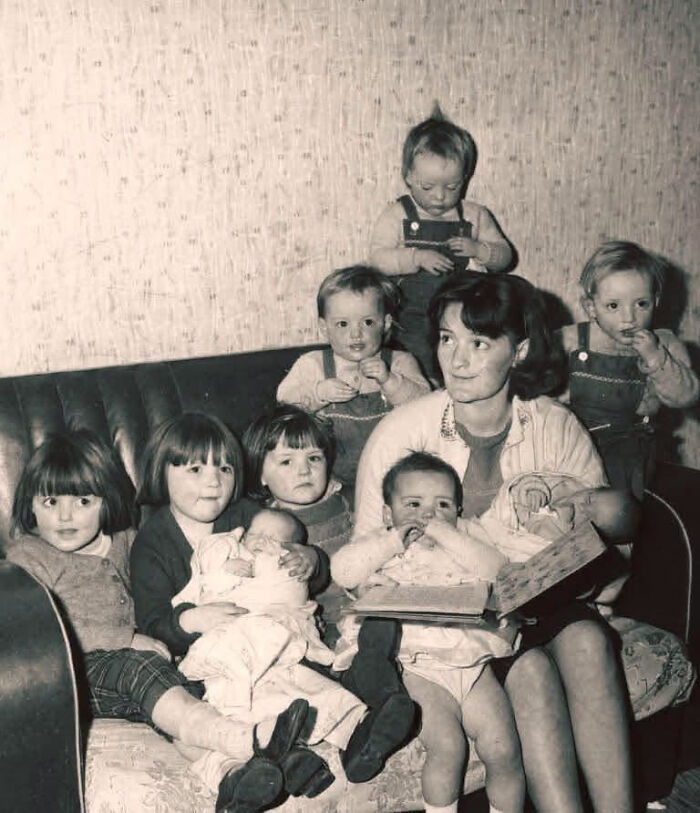 A black and white photo of a woman on a couch surrounded by several young children, representing overlooked women in history.