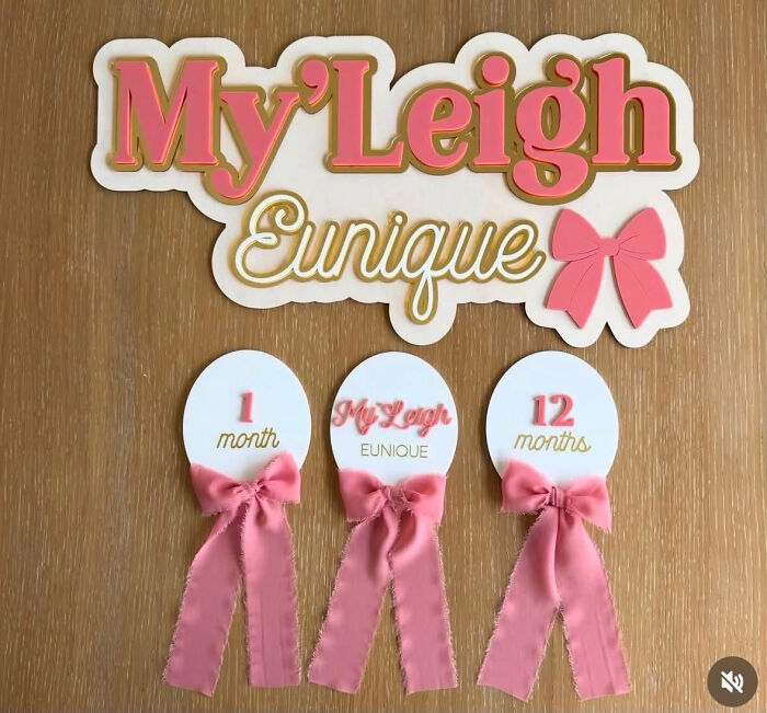 Baby decor featuring the unique names My'Leigh Eunique, with pink bows, on a wooden surface.