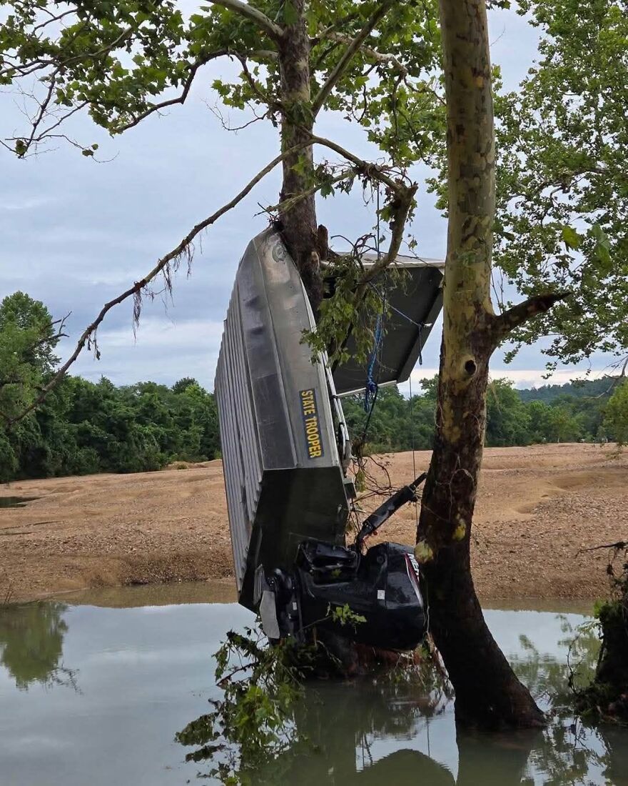 A State Trooper boat caught vertically in tree branches, showing a rough day behind the wheel.