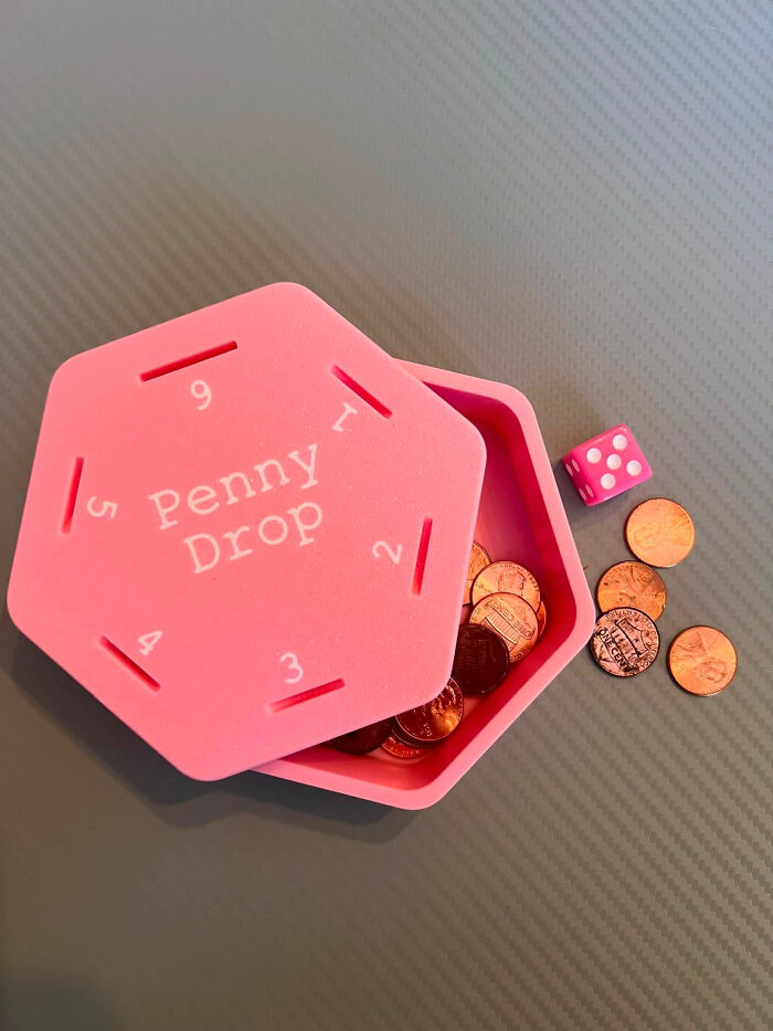 A pink hexagonal Penny Drop game with a d*e and coins, a cool and useful 3D printed game.