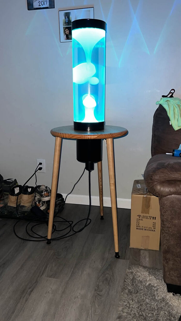 A glowing blue lava lamp, a cool thing created with a 3D printer, sitting on a wooden table.