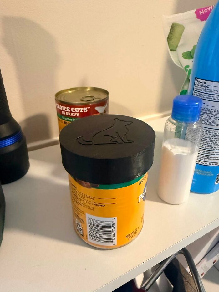 A black 3D-printed lid with a dog silhouette on a container of dog food, a useful thing created with a 3D printer.