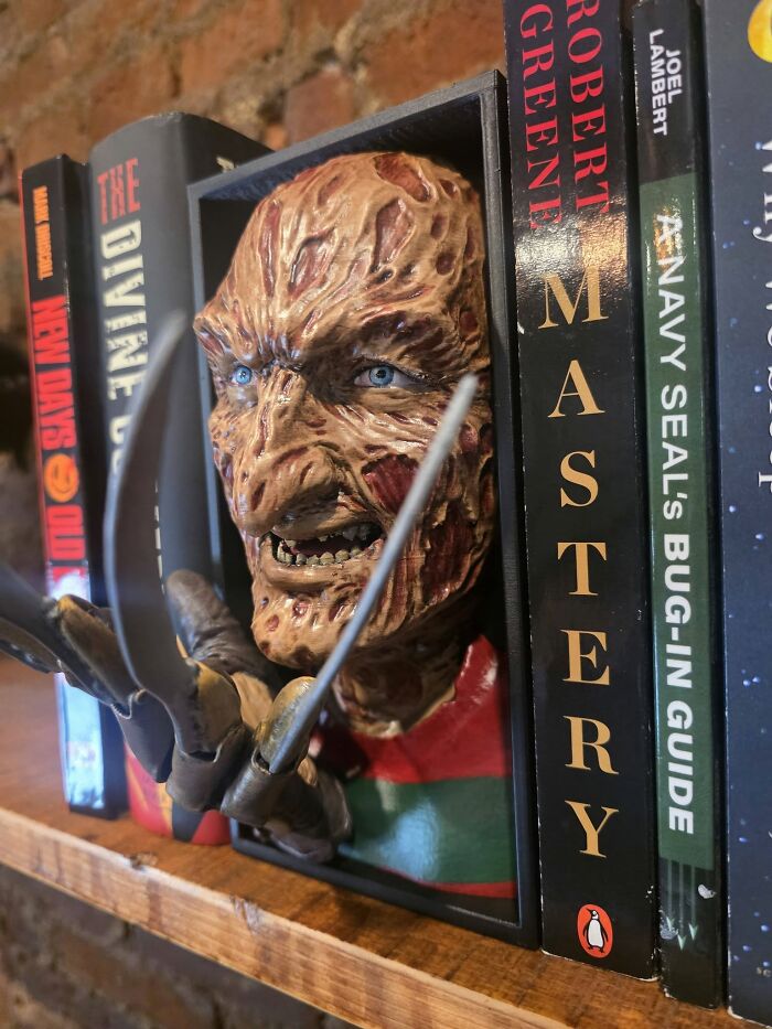 A Freddy Krueger 3D-printed bookend on a shelf, showcasing a cool and useful creation with a 3D printer.