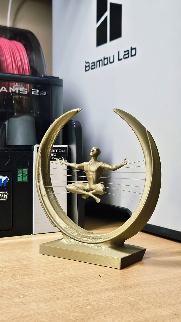 A gold 3D printed figure meditating within a circular frame, cool and useful things created with a 3D printer.