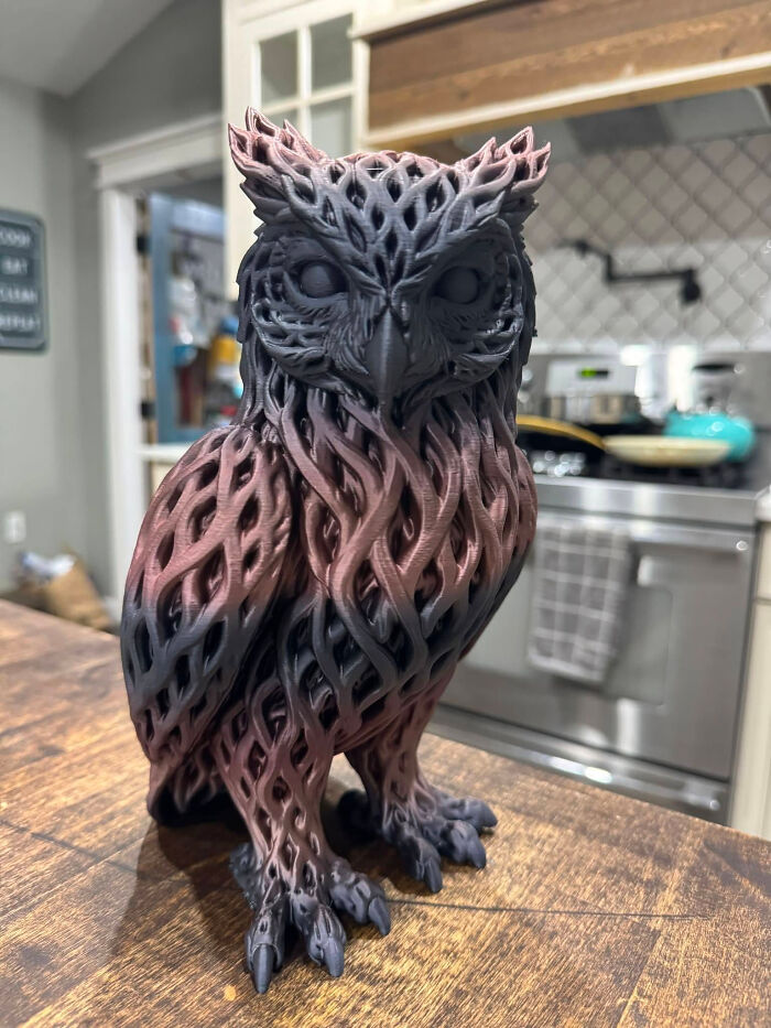 A detailed 3D printed owl with intricate patterns in black and red hues, cool and useful things created with a 3D printer.