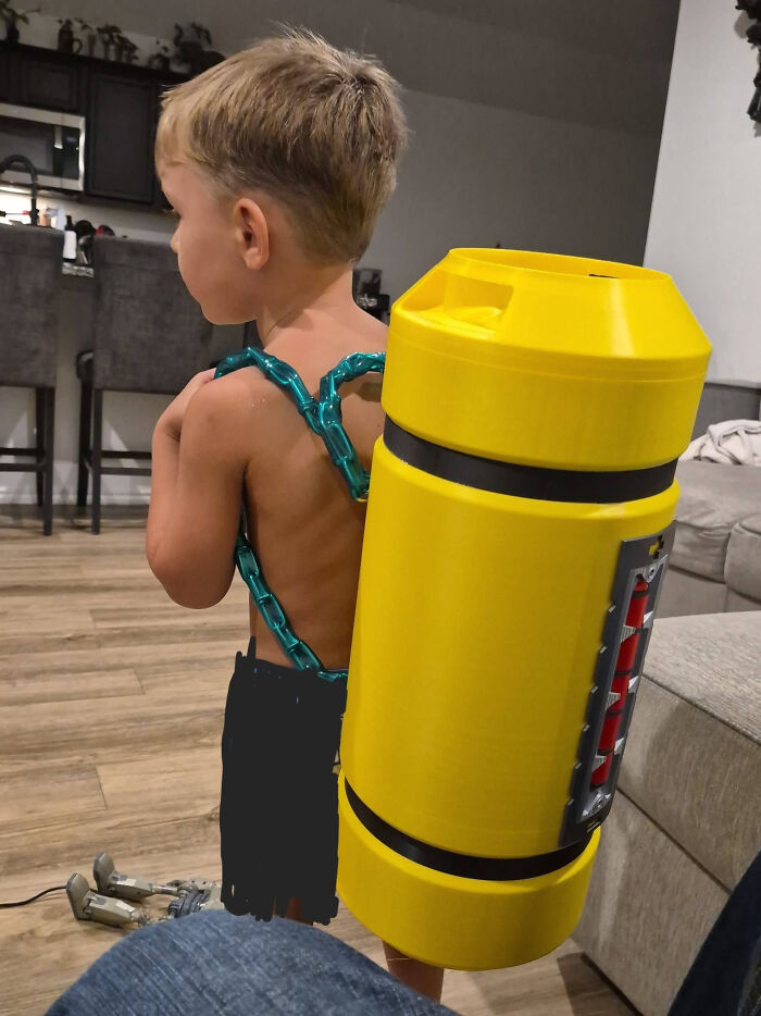 A young boy wearing a large yellow 3D printed backpack. A cool 3D printed item.