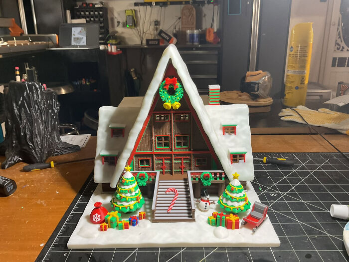 An intricate 3D printed Christmas house diorama with snow, trees, and presents, demonstrating cool things created with a 3D printer.