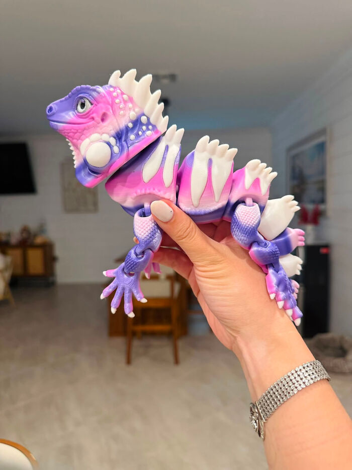A vibrant pink and purple articulated lizard, one of the cool and useful things created with a 3D printer.