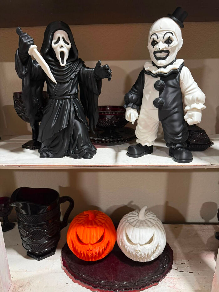 A display of 3D printed horror figurines, including Scream and Art the Clown, with pumpkin decorations.