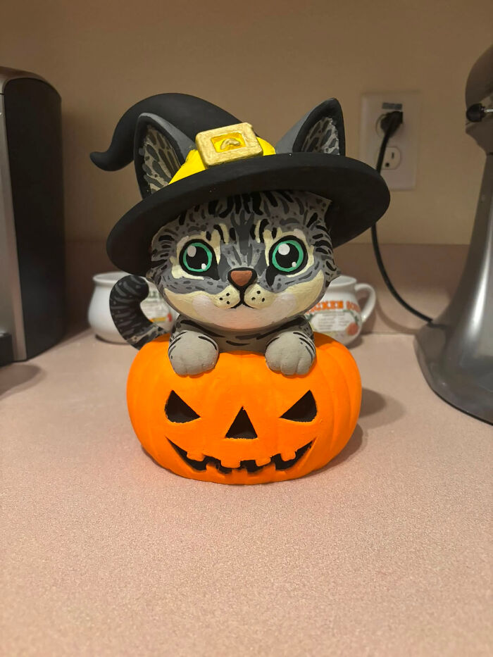 A cute cat figure wearing a witch hat emerging from a pumpkin, a cool 3D printer creation.