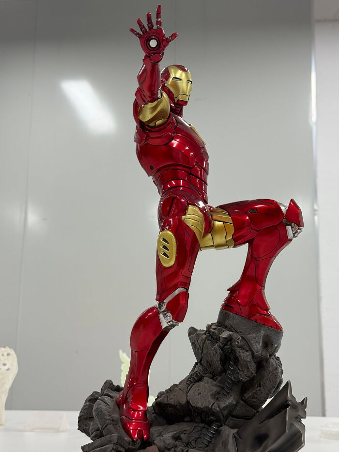 An impressive 3D printer creation of an Iron Man statue in a dynamic pose, showcasing red and gold armor.