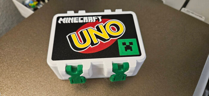 A white Minecraft UNO card box, a useful thing created with a 3D printer, on a brown surface.