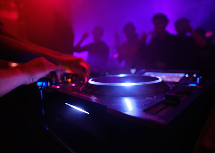 A DJ mixing music at a club, creating an atmosphere where clever comebacks might be shared.