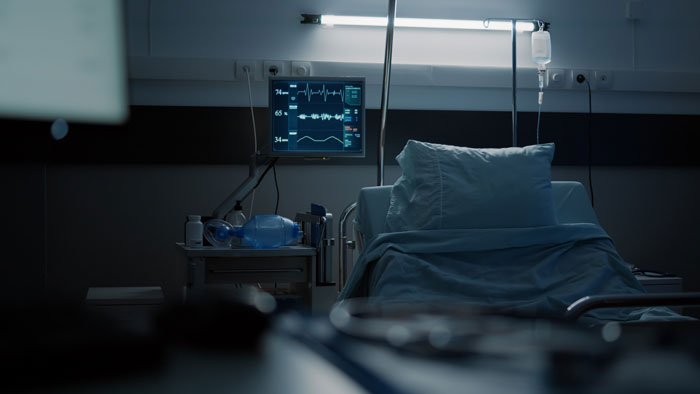 An empty hospital bed with medical monitoring equipment, hinting at the hidden side of hospitals.