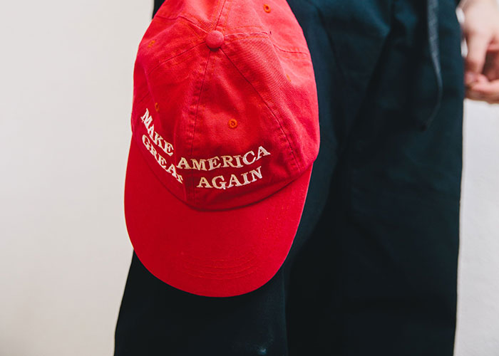 A person holding a red MAGA hat, symbolizing a moment where reality might break.