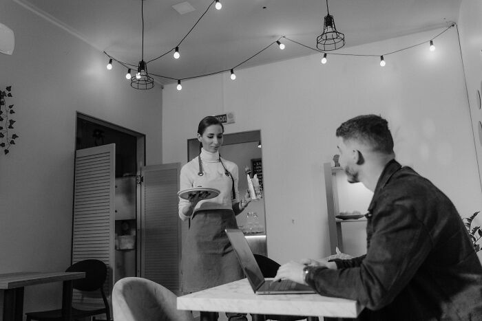 A waitress serves a customer at a cafe, highlighting service industry interactions. Stories of people got fired from jobs.