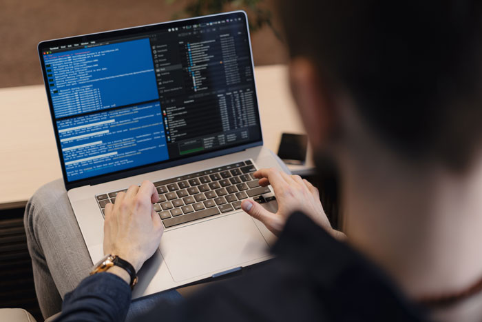 A person coding on a laptop, showing a job-related activity.