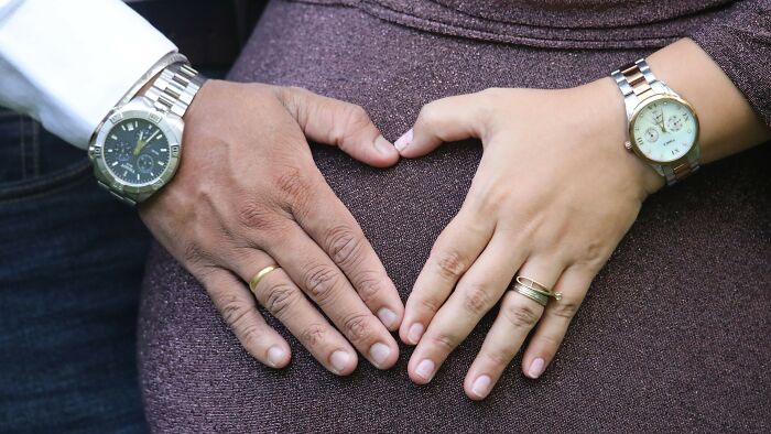 Hands forming a heart shape over a pregnant belly, symbolizing love and family. Learn about family pictures and ex-partners.
