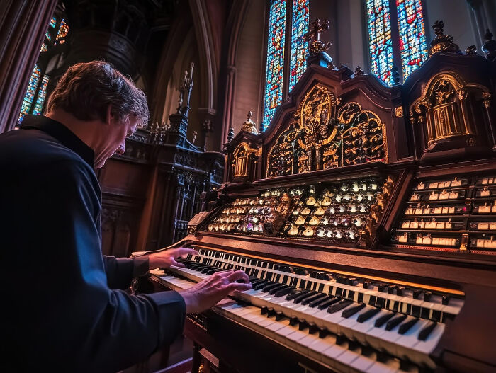A musician playing a grand pipe organ in a church, perhaps a dumb reason someone got fired for song choice.
