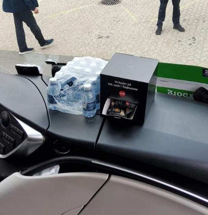 Bottled water and a snack box on a car dashboard, offering a simple and genius solution for travelers.