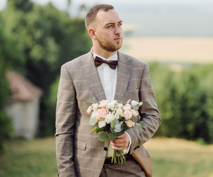 Wedding groom holding a bouquet, looking away, reflecting on his big day. Wedding groom holding a bouquet, looking away, reflecting on his big day.