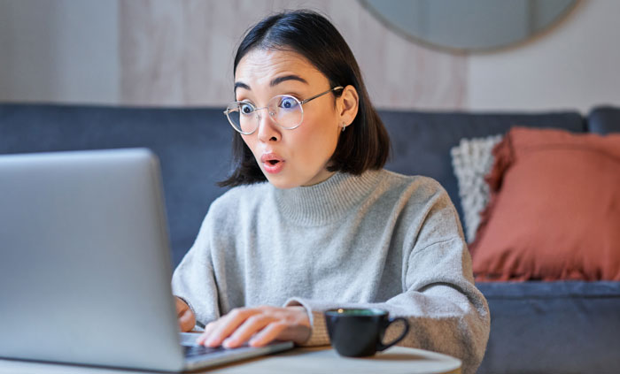 A shocked woman in glasses looks at her laptop screen, discovering a missing business sign video. A shocked woman in glasses looks at her laptop screen, discovering a missing business sign video.