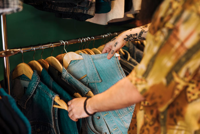 A person browsing through clothes on a rack, seeking surprisingly affordable items.