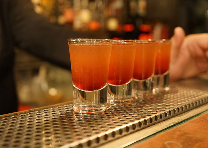 Four shot glasses on a bar counter, symbolizing reasons people no longer look forward to their birthdays.