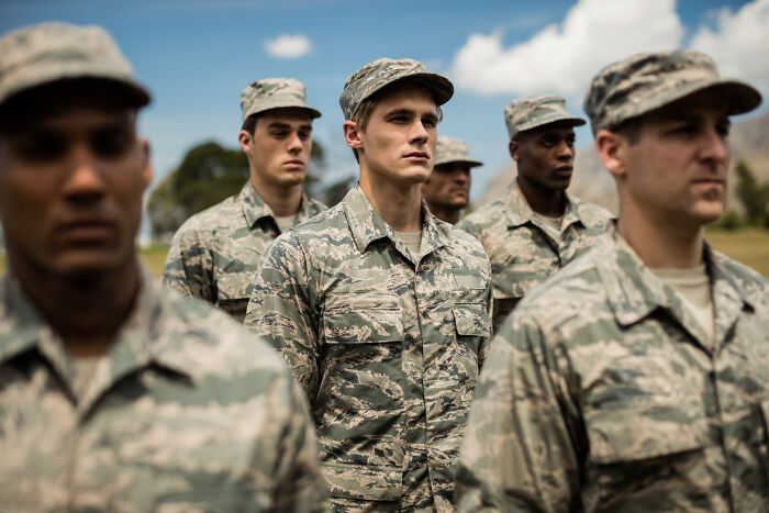 A group of soldiers in uniform standing outdoors, representing stories about guests and house etiquette.