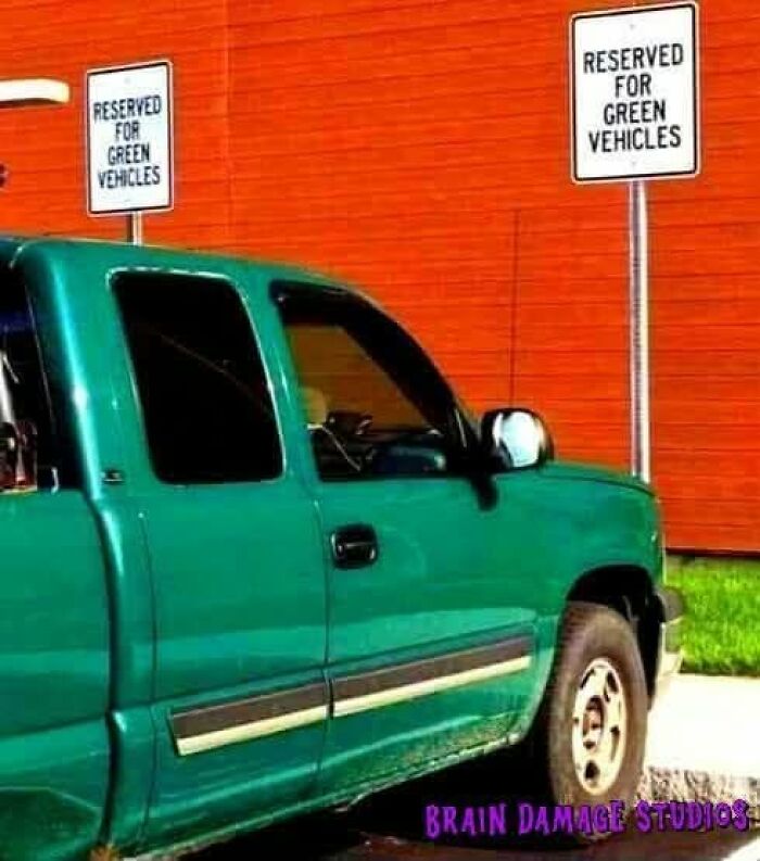 A green pickup truck parked under two signs that say RESERVED FOR GREEN VEHICLES, a ridiculous post about cultural decline.
