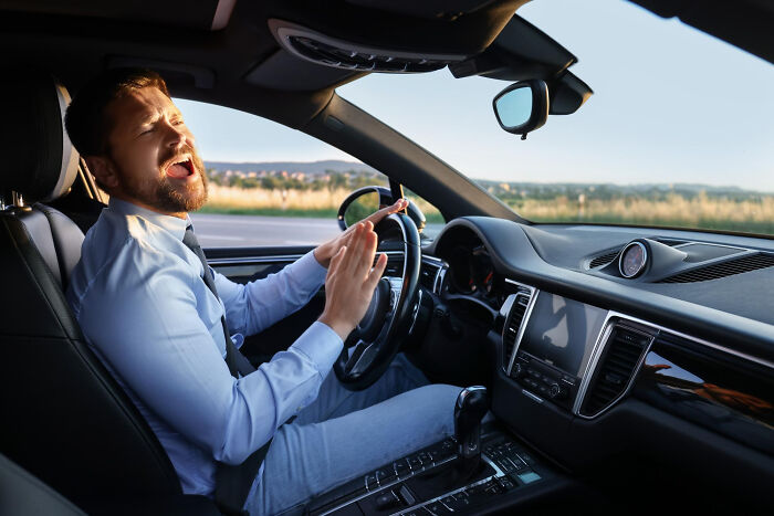 A man in a car with a distressed expression, potentially related to pocket dial stories.