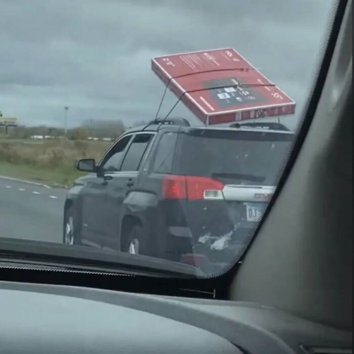A flat-screen TV precariously strapped to a car roof, illustrating a ridiculous post showcasing cultural decline.