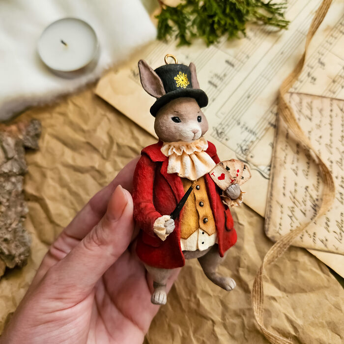Handmade cotton wool creation of a rabbit in a red coat and top hat, holding a fan, by an artist who creates art.