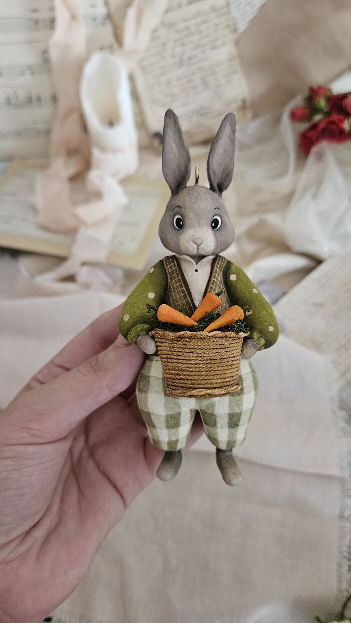 Handmade cotton wool creation of a rabbit in green, holding a basket of carrots, by an artist who creates art.
