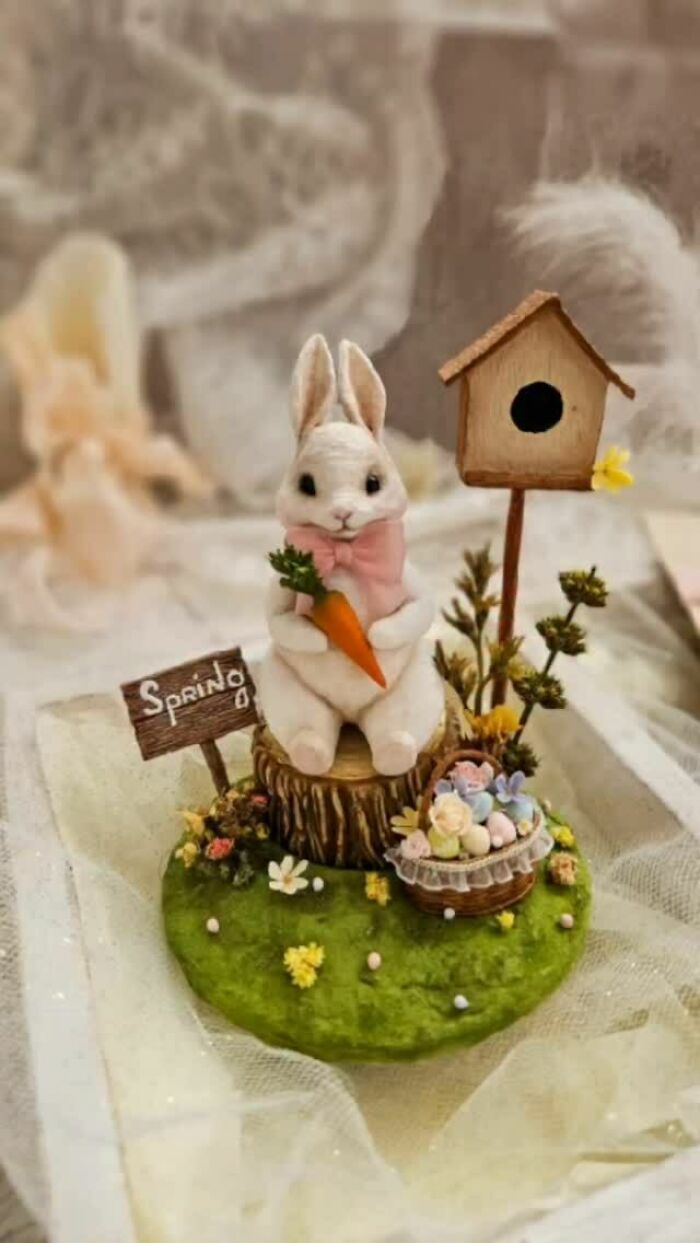 A charming handmade cotton wool creation of a white bunny holding a carrot, set in a spring scene.
