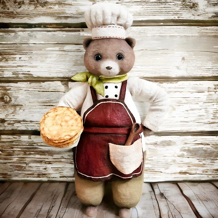 A delightful handmade cotton wool creation of a bear dressed as a chef, holding a stack of pancakes.