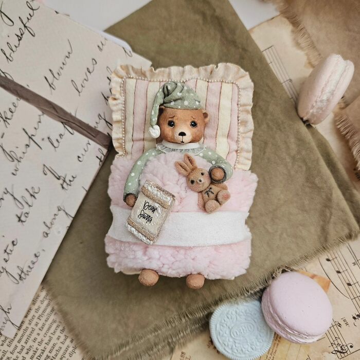 A handmade cotton wool bear creation in pajamas, lying on a pink bed with a Dear Santa letter and a bunny toy.